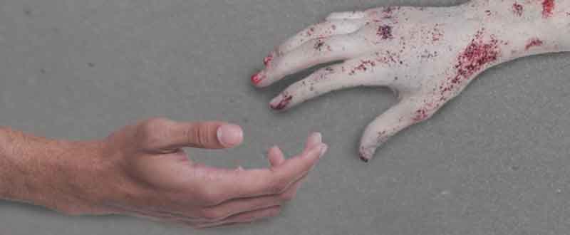 Zombie hand reaching out to healthy person for help